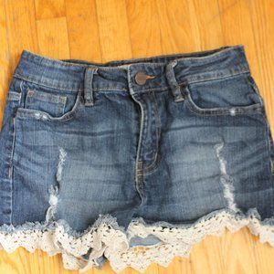 Low-rise/dark wash denim shorts with rips and white lace (Size S).